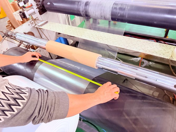 Operator checking polyethylene film width during production